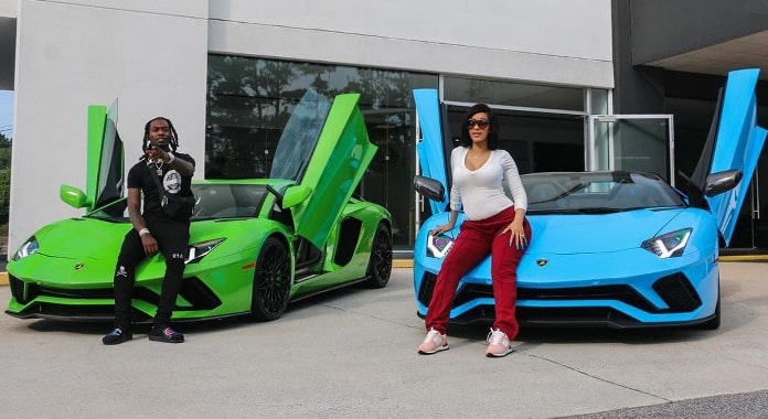 Cardi B standing in front of her blue Lamborghini while Offset in front of his green Lamborghini